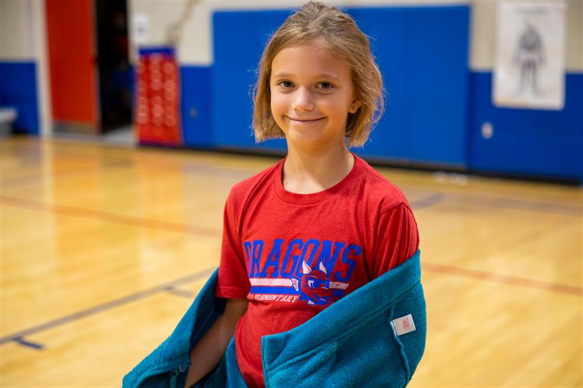 A girl wearing a red t-shirt smiles